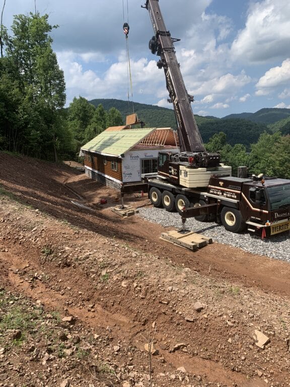 a crane setting the roof on a prefab login cabin in parson west virginia