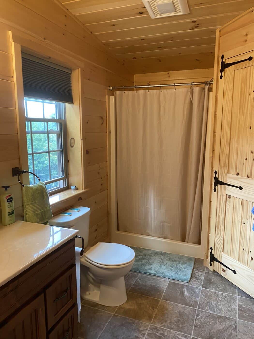 huge master bath with walk in shower and window inside of a prefab log cabin