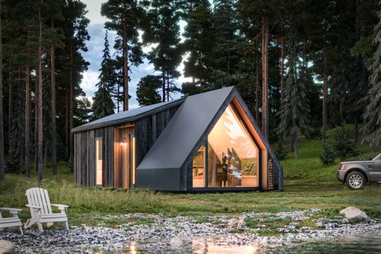 A modern style cabin in a clearing near a small body of water