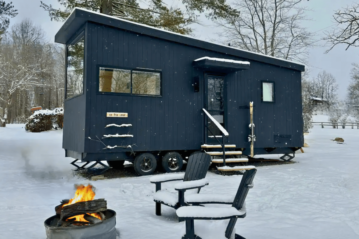 blue park model tiny home in snow with fire pit out front