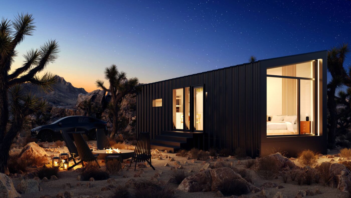 park model tiny home at night with lights on showing bedroom and kitchen space inside