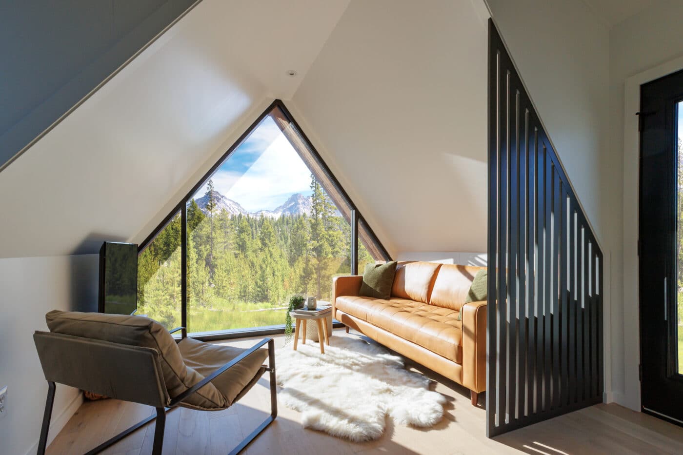 inside view of a frame tiny home with a shaped window overlooking forest