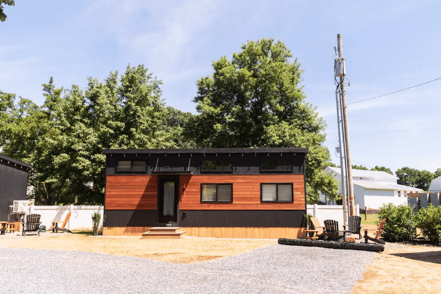 park model tiny home with black and wooden siding on permanent foundation